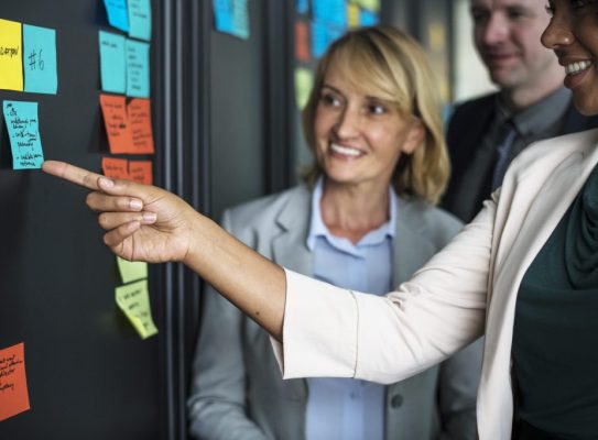 Businesspeople planning tasks with sticky notes